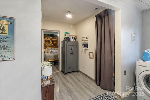 laundry area with crown molding, washer / dryer, and light wood-type flooring