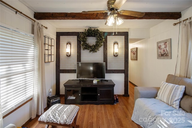 living room featuring beamed ceiling, ceiling fan, and light wood-type flooring