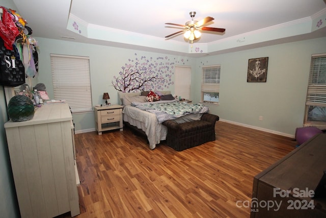 bedroom with crown molding, ceiling fan, a tray ceiling, and hardwood / wood-style flooring