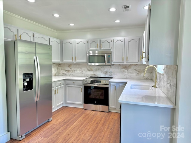 kitchen with light wood-type flooring, crown molding, sink, stainless steel appliances, and white cabinetry