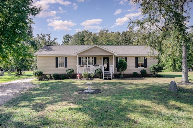 ranch-style home featuring covered porch and a front yard