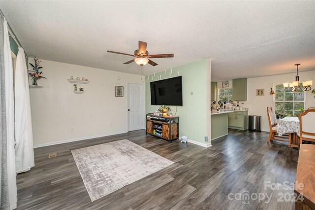 living room featuring baseboards, ceiling fan with notable chandelier, dark wood-style flooring, and a textured ceiling