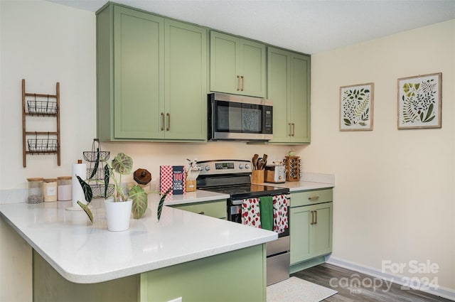 kitchen with dark wood-style flooring, stainless steel appliances, a peninsula, and green cabinets