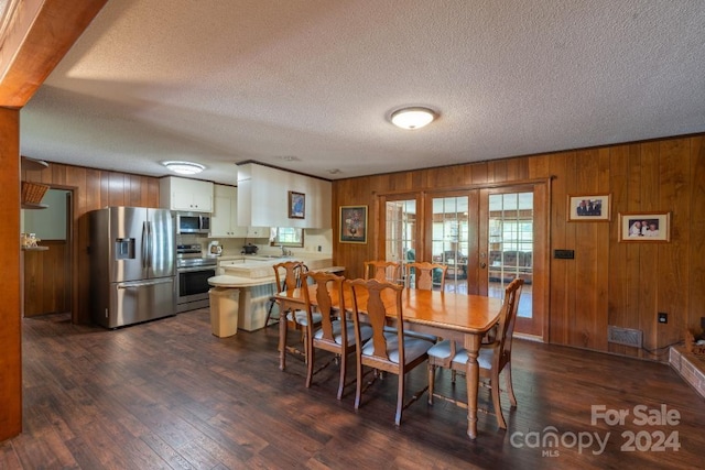 dining area with french doors, a textured ceiling, dark hardwood / wood-style flooring, and wooden walls