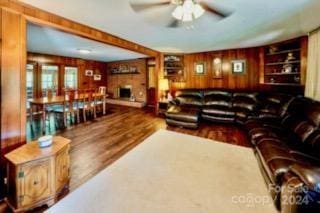 living room featuring wooden walls, hardwood / wood-style flooring, and ceiling fan