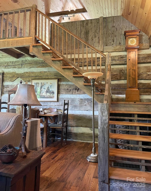 stairway featuring lofted ceiling, wood ceiling, wooden walls, and hardwood / wood-style flooring