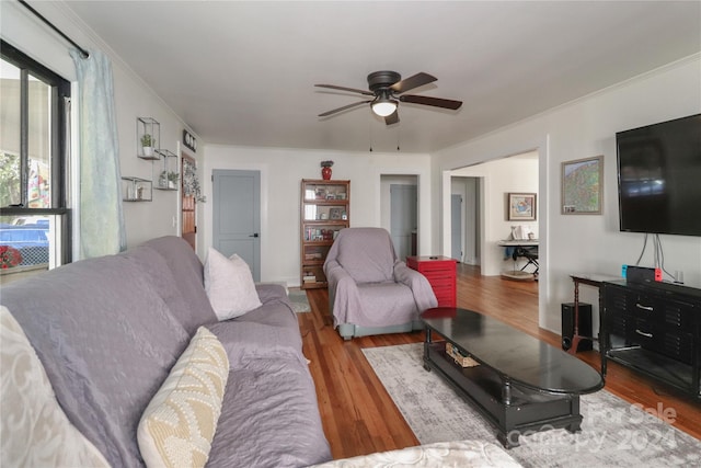 living room with ornamental molding, light hardwood / wood-style floors, and ceiling fan