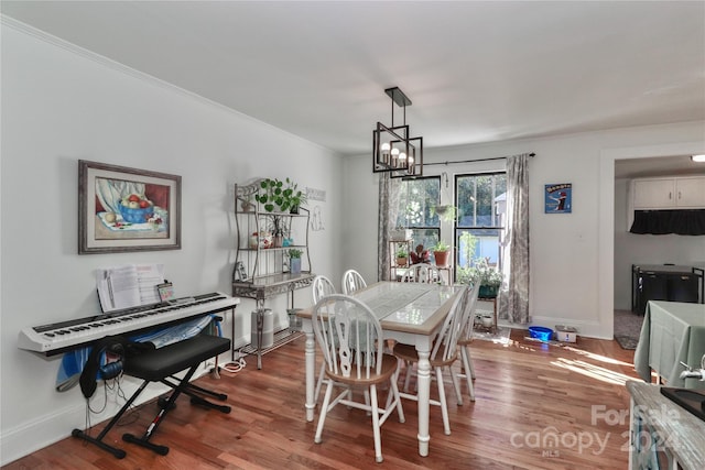 dining room with a notable chandelier, hardwood / wood-style flooring, and crown molding