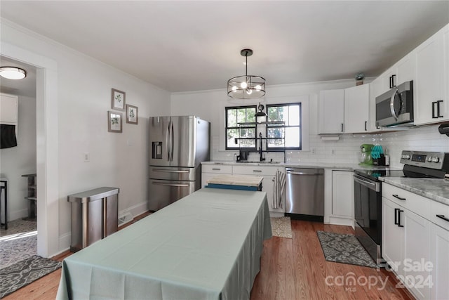 kitchen featuring wood-type flooring, a center island, white cabinets, pendant lighting, and appliances with stainless steel finishes