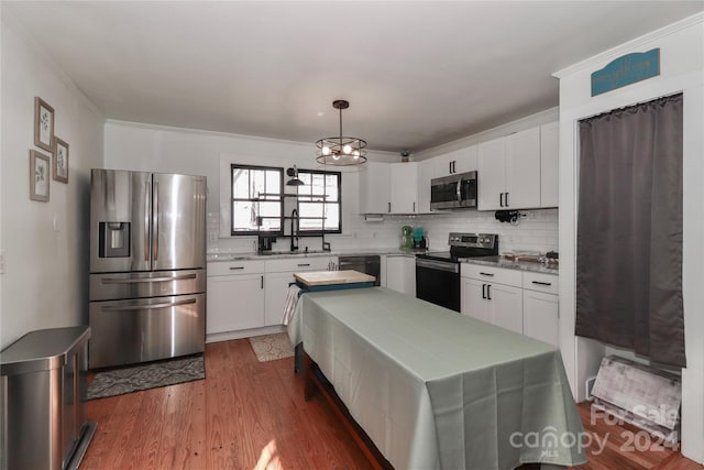 kitchen with hardwood / wood-style flooring, hanging light fixtures, stainless steel appliances, an inviting chandelier, and white cabinets