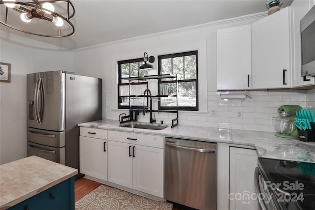 kitchen featuring appliances with stainless steel finishes, sink, white cabinetry, light hardwood / wood-style floors, and light stone counters