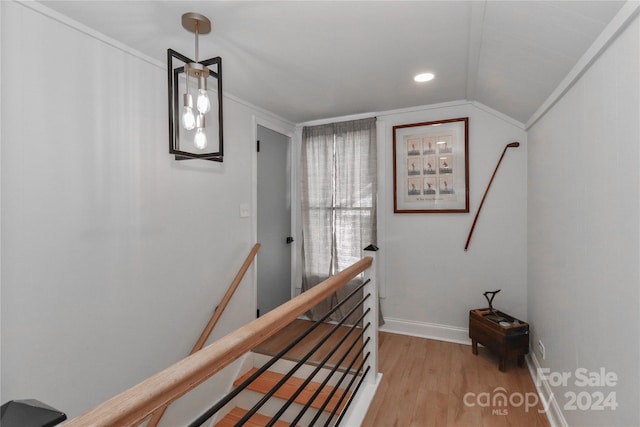 stairway with crown molding, vaulted ceiling, and wood-type flooring