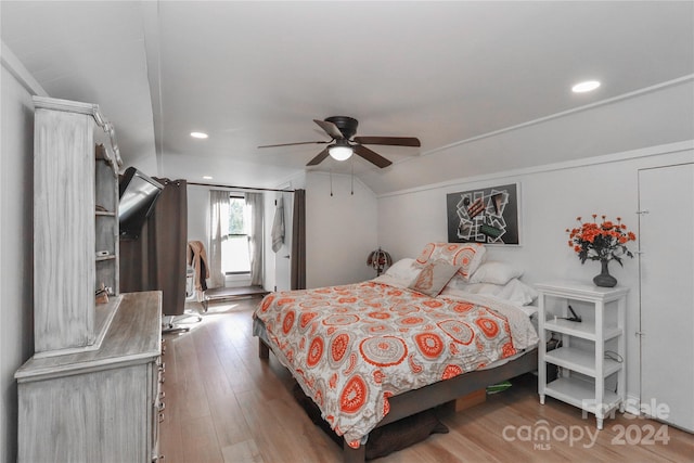 bedroom with ceiling fan, hardwood / wood-style flooring, and vaulted ceiling