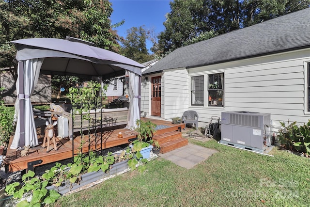 exterior space with a gazebo, cooling unit, a front lawn, and a wooden deck