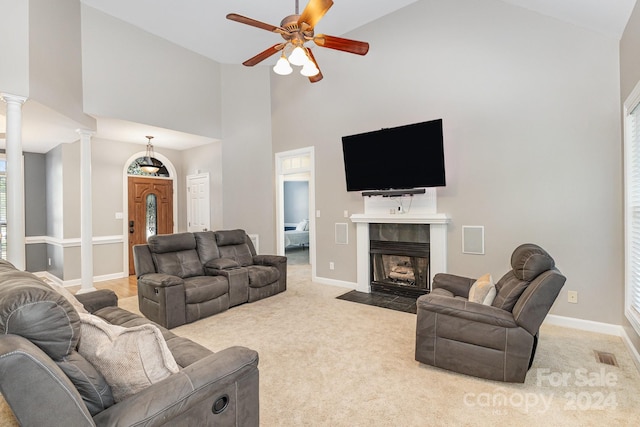 carpeted living room with ceiling fan, high vaulted ceiling, a fireplace, and decorative columns