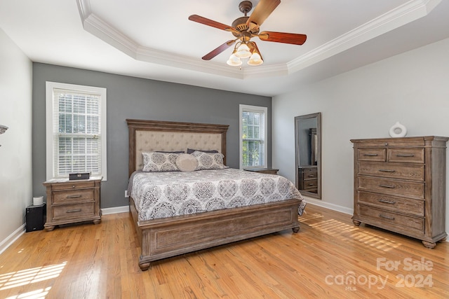 bedroom featuring ceiling fan, a raised ceiling, ornamental molding, and light wood-type flooring