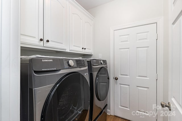 laundry room with cabinets, hardwood / wood-style floors, and washing machine and dryer