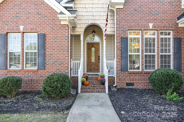 view of exterior entry featuring brick siding and crawl space