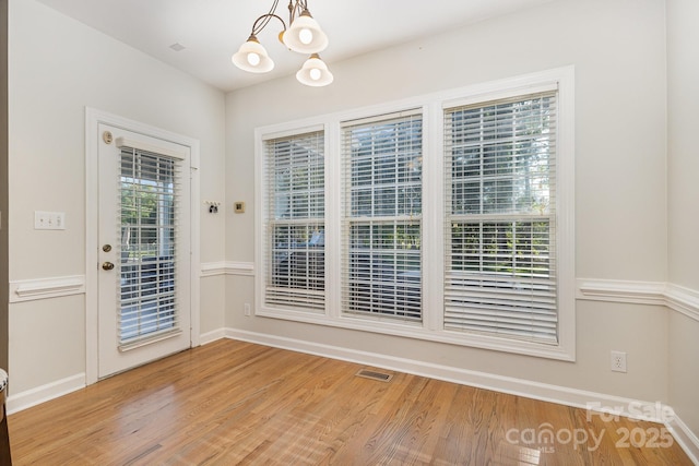 9404 Perimeter Ct, Zebulon, NC 27597 - unfurnished dining area featuring a chandelier and wood finished floors