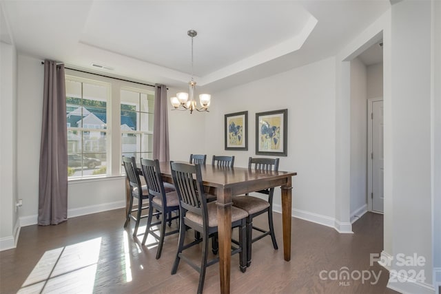 dining room with a notable chandelier, dark hardwood / wood-style floors, and a raised ceiling