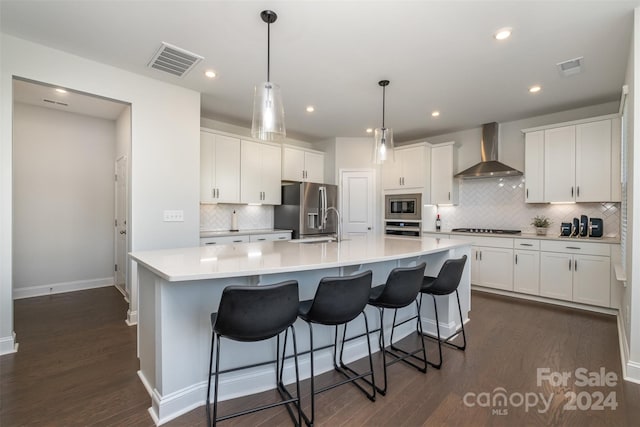 kitchen featuring dark hardwood / wood-style flooring, a spacious island, wall chimney range hood, and stainless steel appliances