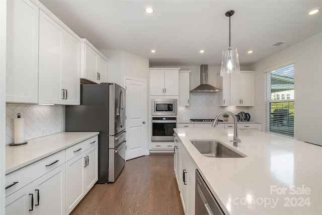 kitchen featuring white cabinets, wall chimney range hood, sink, dark hardwood / wood-style flooring, and stainless steel appliances