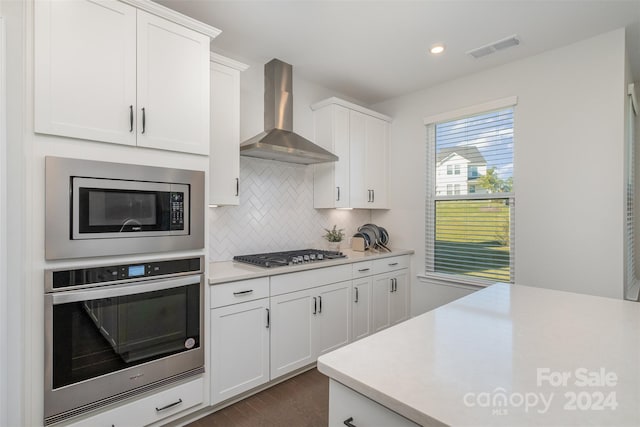 kitchen with white cabinets, wall chimney exhaust hood, and stainless steel appliances