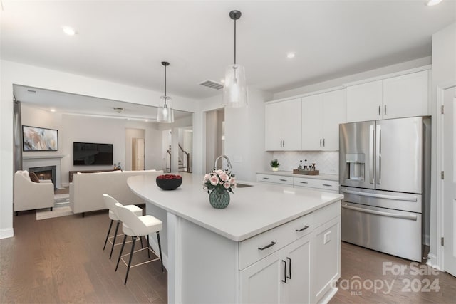 kitchen featuring white cabinets, sink, stainless steel fridge with ice dispenser, and an island with sink