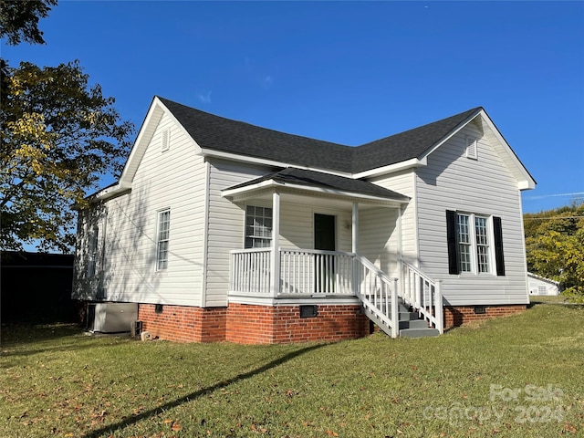 view of front of house featuring cooling unit, a porch, and a front yard