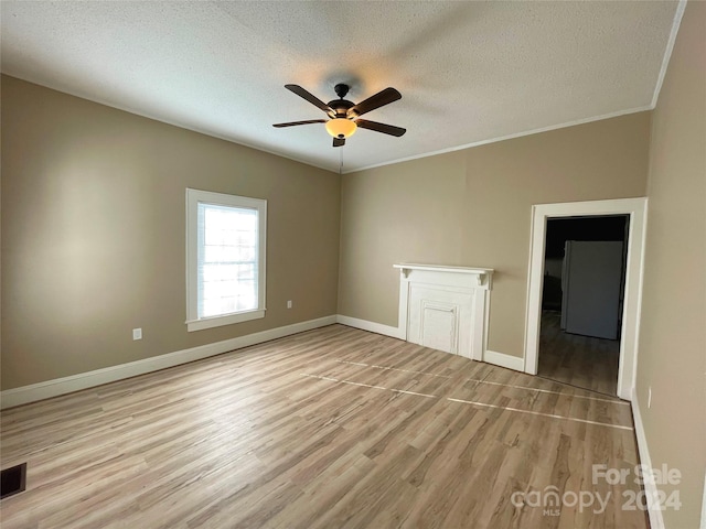 empty room featuring a textured ceiling, ceiling fan, ornamental molding, and light hardwood / wood-style flooring