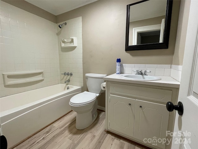 full bathroom with tiled shower / bath combo, hardwood / wood-style flooring, vanity, and toilet