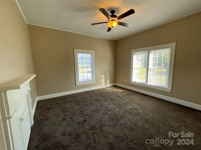 empty room featuring ceiling fan, dark carpet, ornamental molding, and a textured ceiling