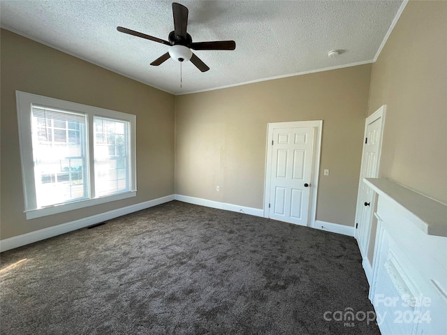 unfurnished room featuring ceiling fan, dark carpet, ornamental molding, and a textured ceiling