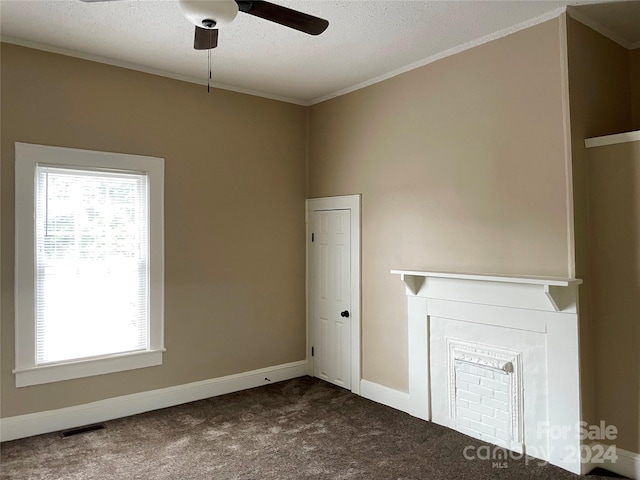 carpeted spare room with a fireplace, ceiling fan, crown molding, and a textured ceiling