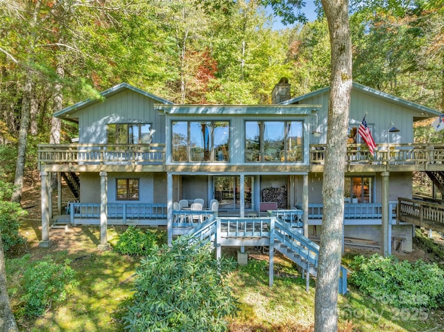 rear view of house featuring a sunroom and a deck