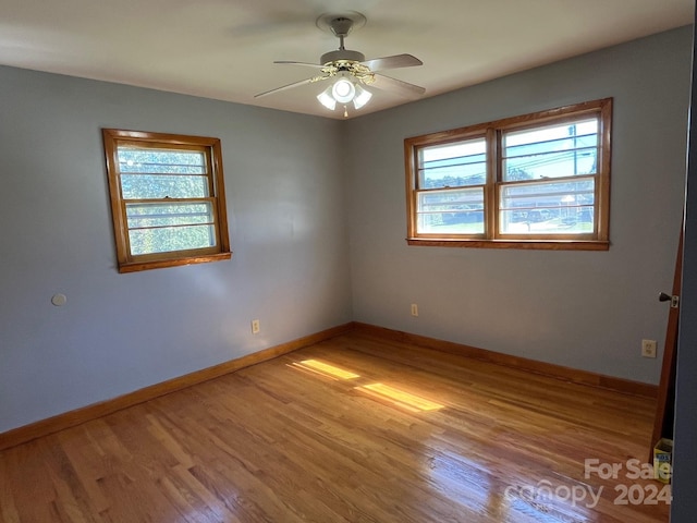 spare room featuring ceiling fan, hardwood / wood-style flooring, and plenty of natural light