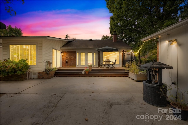 back house at dusk featuring a patio and french doors