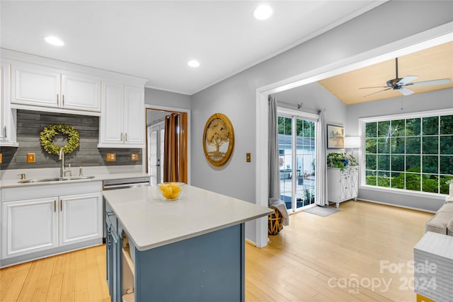 kitchen featuring a kitchen island, sink, white cabinets, and backsplash