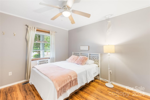 bedroom with crown molding, hardwood / wood-style floors, cooling unit, and ceiling fan