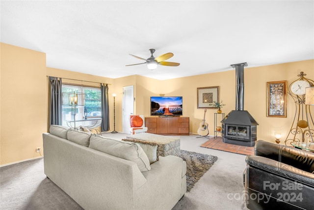 carpeted living room featuring a wood stove and ceiling fan