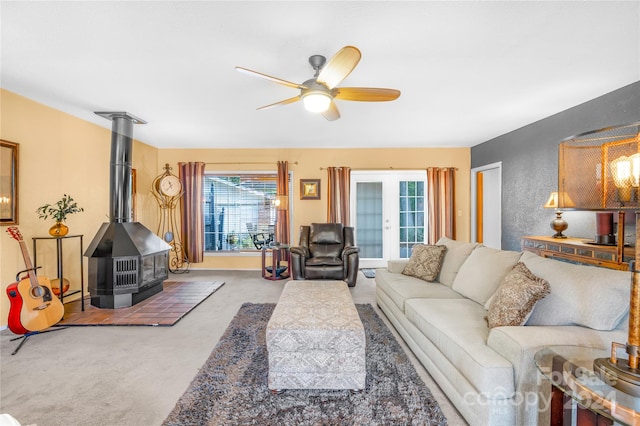 living room featuring carpet, ceiling fan, a wood stove, and french doors