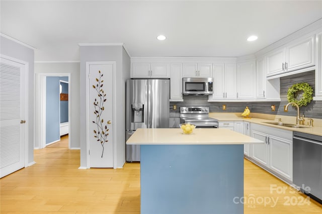 kitchen with white cabinetry, stainless steel appliances, light hardwood / wood-style flooring, and a kitchen island