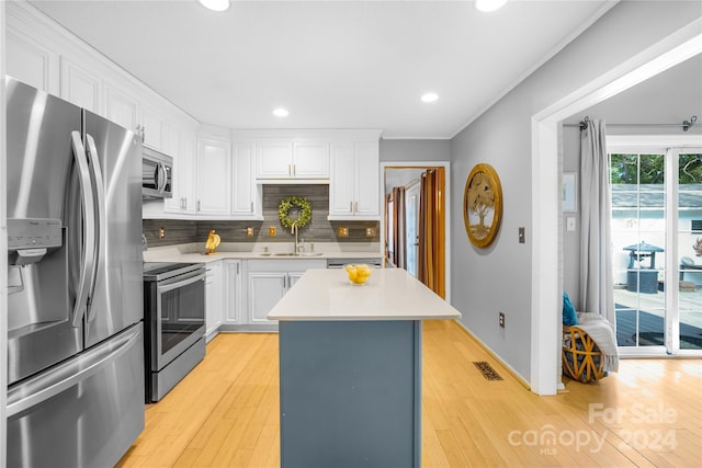 kitchen with light hardwood / wood-style flooring, a center island, white cabinets, and stainless steel appliances