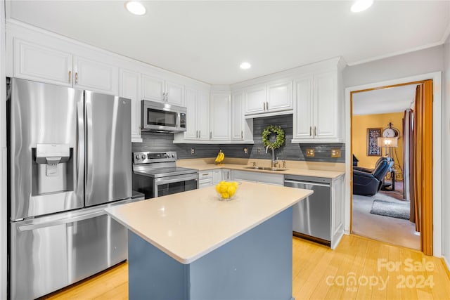 kitchen with backsplash, a kitchen island, white cabinetry, light wood-type flooring, and stainless steel appliances