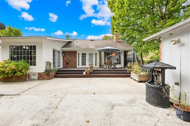 rear view of property featuring french doors, a patio area, and a wooden deck