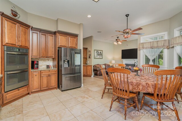 kitchen with decorative backsplash, light stone counters, ceiling fan, light tile patterned flooring, and stainless steel appliances