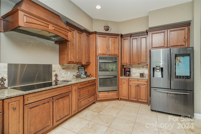 kitchen featuring appliances with stainless steel finishes, premium range hood, tasteful backsplash, and light stone counters