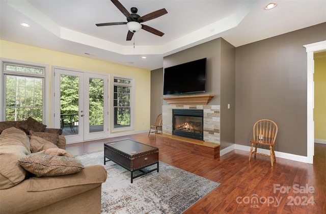 living room featuring hardwood / wood-style floors, a raised ceiling, and ceiling fan