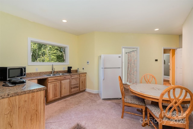 kitchen with light colored carpet, sink, and white refrigerator