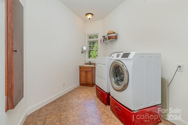 clothes washing area featuring cabinets, washer and dryer, and sink